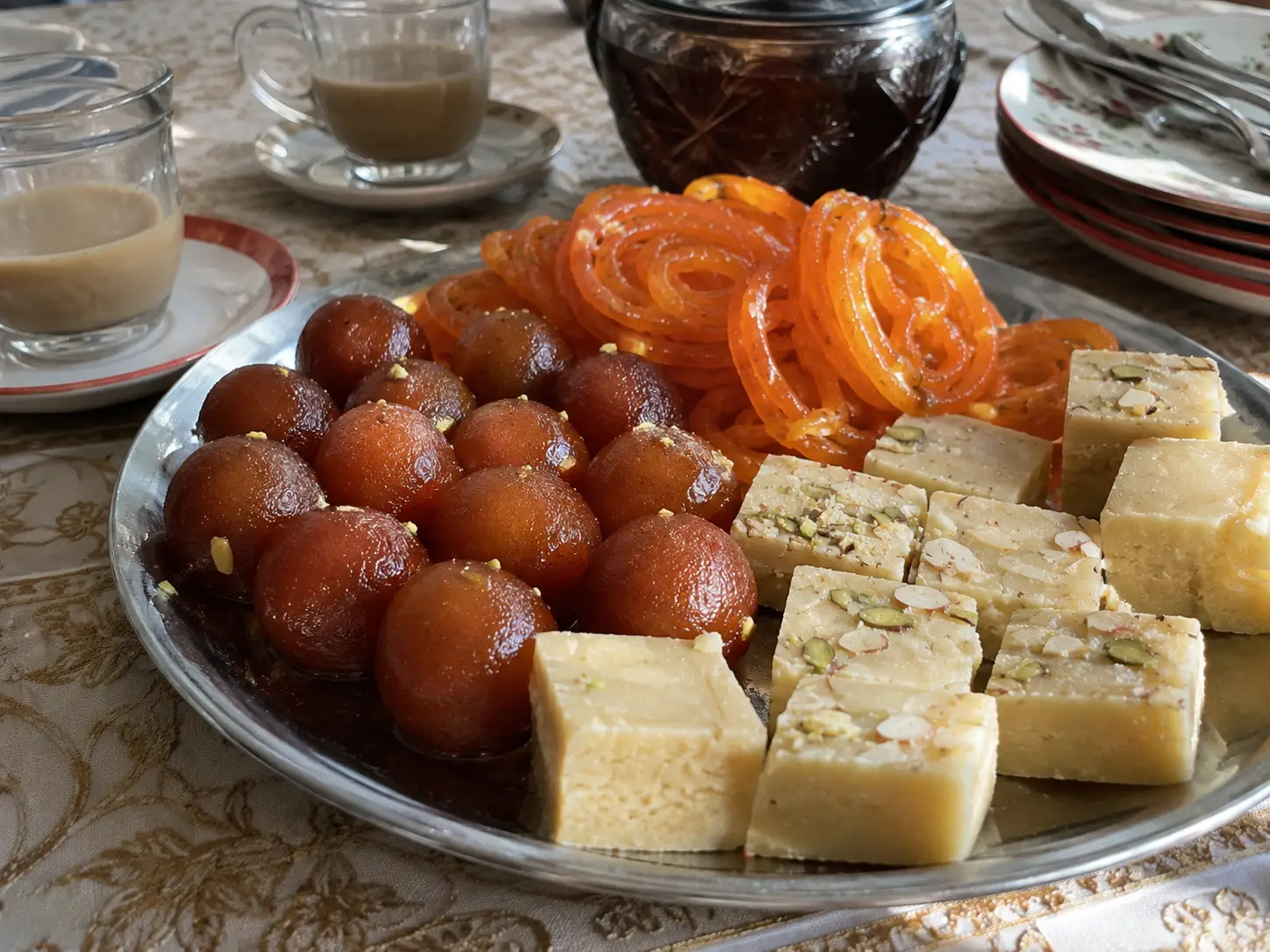 Popular Pakistani  Desserts & Sweets: mithai, including gulab jamun, jalebi, and barfi, on a decorative platter